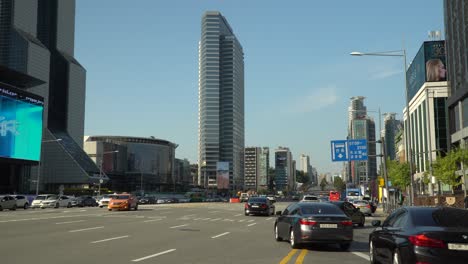 View-wide-freeway-main-road-of-Seoul-near-Coex,-South-Korea-with-the-Asem-Tower-ahead-and-the-Trade-Tower-to-the-left,-cars-and-taxies-turning