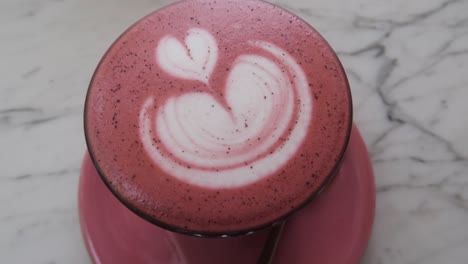 Eine-Tasse-Rosa-Chai-Latte-Art-Mit-Goldenem-Löffel