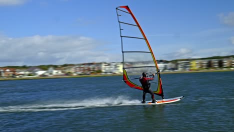 Windsurfer-blown-along-by-strong-sea-breeze-balances-on-his-surf-board-at-West-Kirby-marine-lake