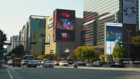 Cars-start-moving-on-green-traffic-light-on-Teheran-ro-Road-in-Seoul-near-Grand-Intercontinental-Hotel-COEX,-Hyundai-Department-Store,-Samseong-Station-in-Autumn,-Huge-Outdoor-Wall-Ad-Billboards