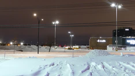 Yellow-Bulldozers-Carry-out-Snow-Removal-During-a-Cold-Night-in-Winter,-Lighting-and-Cloudy-sky