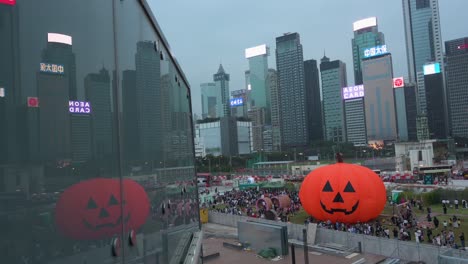 Eine-Riesige,-10-Meter-Hohe-Aufblasbare-Halloween-Kürbisinstallation-Wird-Von-Der-Öffentlichkeit-Während-Der-Halloween-Feierlichkeiten-Genossen,-Während-Im-Hintergrund-In-Hongkong-Wolkenkratzer-Zu-Sehen-Sind