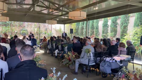 4K-video-of-a-wedding-ceremony-where-the-bride-and-groom-are-seen-in-the-background-in-front-of-the-judge-saying-their-vows-while-a-photographer-takes-pictures-and-a-choir-sings