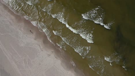 Einsame-Person,-Die-An-Der-Sandigen-Küste-Mit-Rollenden-Wellen-In-Der-Ostsee-Spaziert