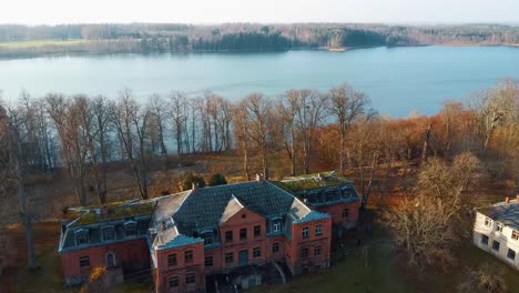 Old-Red-Brick-House,-Katvari-Manor-in-Latvia-and-Katvaru-Lake-in-the-Background