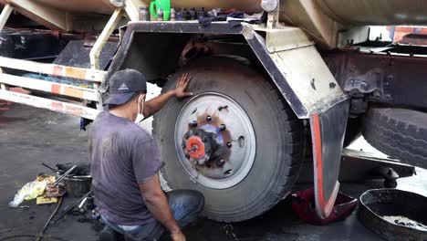 Mecánico-De-Camiones-Cambiando-Neumáticos-De-Camiones,-Colocando-La-Primera-Rueda