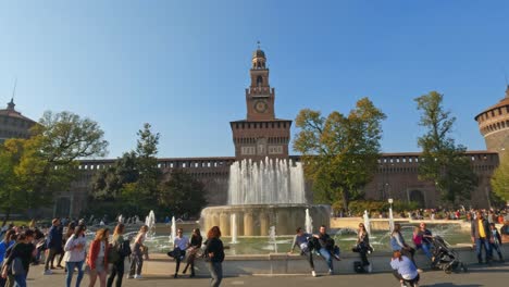 External-panning-view-of-medieval-Sforza-Castle-or-Castello-Sforzesco-in-Milan-with-tourists-and-fountain