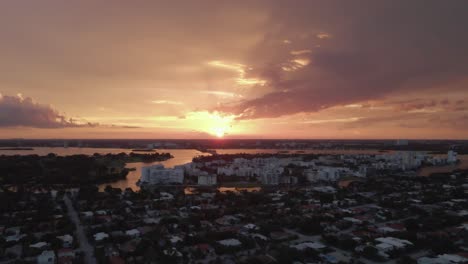 Peach-colored-gold-sunset-aerial-rises-over-Indian-Creek,-Surfside-FLA
