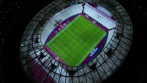 Aerial-view-above-modern-official-West-Ham-United-club-football-stadium-arena-at-night-orbit-left
