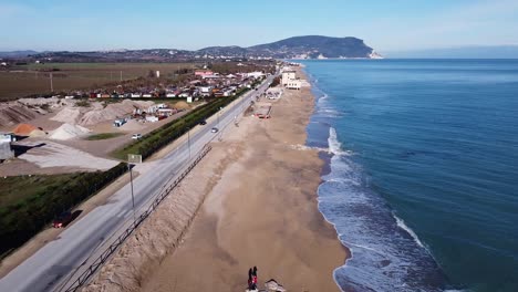 aerial-view-of-an-Italian-coastline-with-morning-light---following-a-car-on-the-seafront-road-with-the-adriatic-sea-on-the-right-and-the-Mount-Conero-on-the-background