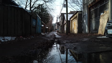 Tilt-up-from-reflections-in-water-puddle-to-reveal-a-vacant-back-alley-in-Toronto