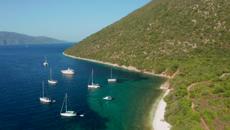 Aerial-flyover-touristic-destination,-yacht´s-anchored-on-Pristine-Turquoise-Antisamos-beach,-Greece