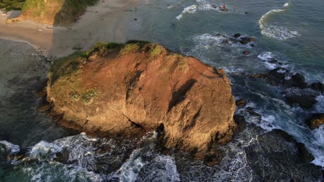 Drone-slowly-approaching-a-giant-rock-at-playa-grande-in-Tamarindo,-Costa-Rica