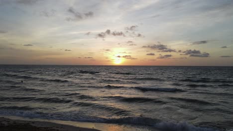 Dark-golden-ocean-sunrise-with-sand-beach-and-dramatic-red-sky-horizon