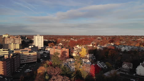 Drone-passes-apartment-building-and-autumn-leaves-in-suburbs-of-Stamford,-CT
