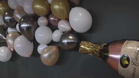 Ballondisplay-In-Form-Einer-Champagnerflasche,-Die-Ein-Getränk-Versprüht-Und-An-Der-Wand-Hängt