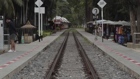Eine-Statische-Aufnahme-Aus-Der-Mitte-Der-Bahnstrecke-Und-Des-Bahnsteigs-Des-Bahnhofs-Kwai-Bridge,-Einem-Wahrzeichen-Aus-Dem-Zweiten-Weltkrieg-Und-Einem-Beliebten-Touristenziel-In-Kanchanaburi,-Thailand