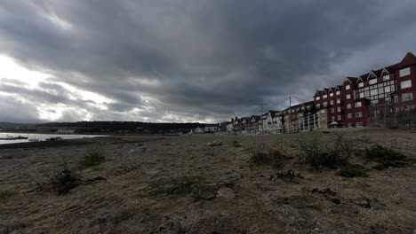 Stormy-morning-cloudy-timelapse-over-British-seaside-town-sandy-harbour-shoreline