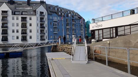 Tourists-walking-at-the-waterfront-of-the-harbor-of-Alesund,-Norway