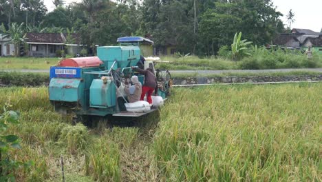 Yogyakarta,-Indonesia---Dec-11,-2021:-Combine-harvester-machine-with-rice-paddy-field