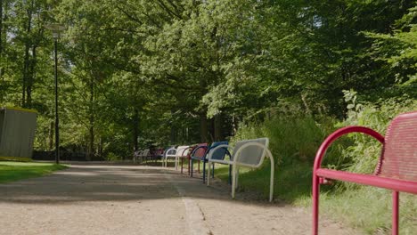 Benches-in-Different-Colors-Blue,-Red-and-White-at-Annelund-Park-in-Borås-Sweden,-Medium-Shot-Tracking-Forward