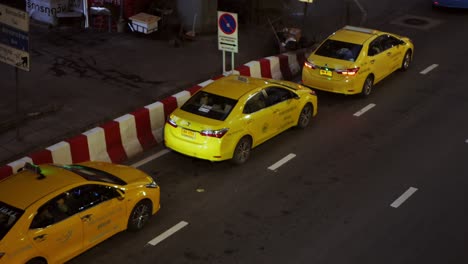 Gelbe-Taxis-Stehen-Abends-Nach-Der-Arbeit-Und-Der-Situation-Der-Covid-19-epidemie-In-Bangkok,-Thailand-An,-Um-Passagiere-Vor-Einem-Einkaufszentrum-Abzuholen