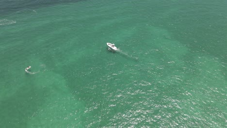Luftaufnahmen-über-Mehrfarbigem-Parasailing-Und-Boot-Im-Seichten-Grünen-Wasser