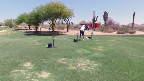 Back-to-camera-golf-practices-driving-at-the-driving-range-at-Greyhawk-Golf-Course,-Scottsdale,-Arizona
