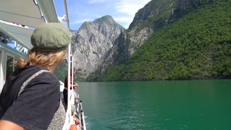 Young-female-tourist-sightseeing-onboard-a-ferry-on-the-stunning-Komani-Lake-in-Northern-Albania,-Europe