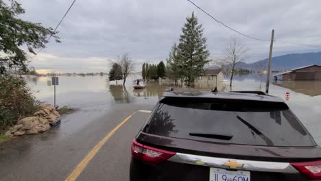 Car-Parked-at-Road-Waters-Edge-with-View-of-Flooded-Homes-and-Farmland,-Abbotsford,-British-Columbia,-Canada,-Handheld-Shot