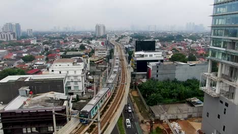 MRT-train-on-high-tracks-and-road-traffic-in-Jakarta,-backward-aerial
