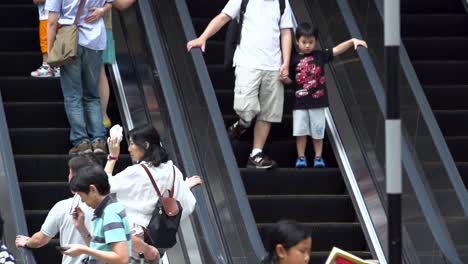 Asian-people-walk-and-use-escalator-At-mall-shopping-center,-slow-motion-of-everyday-city-life,-or-commuter-urban-lifestyle-concept