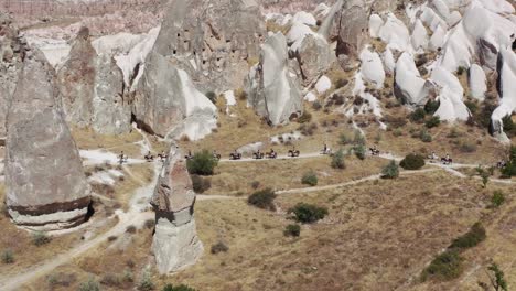 Aerial-view-of-riders-with-horses-walking-through-the-tufa-landscape-of-the-UNESCO-World-Heritage-Site-Goreme,-Cappadocia,-central-Anatolia,-Turkey,-Asia