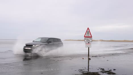 Coches-De-Lujo-Caros-Conduciendo-A-Través-De-Agua-Salada-En-Una-Carretera-De-Playa