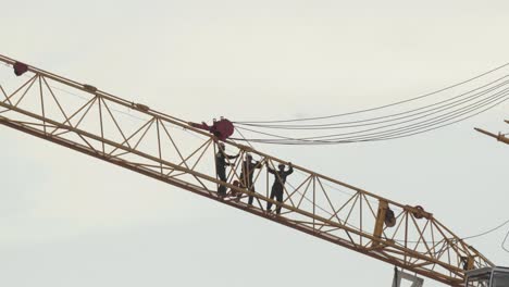 A-shot-of-Thai-construction-workers-assembling-a-crane-on-the-site-of-a-new-development,-the-men-pulling-heavy-duty-cables-which-operate-the-arm-of-the-crane-in-Pathum-Thani,-Thailand