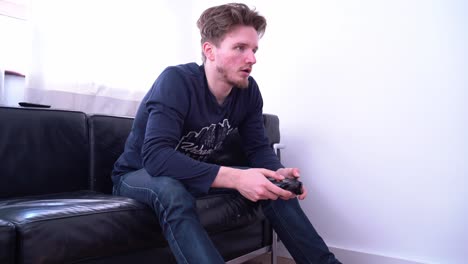 Man-playing-Xbox-One-video-game-sitting-on-a-couch,-medium-shot