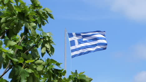 Bandera-Griega-Ondeando-En-El-Viento-Frente-A-Un-Cielo-Azul-Claro,-En-Cámara-Lenta