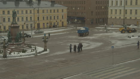 Truck-and-snowplow-bulldozer-clear-the-snow-around-the-statue-of-Emperor-Alexander-II-in-front-of-Helsinki-Cathedral,-Senate-Square