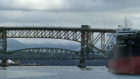 Parken-Eines-Asiatischen-Containerschiffs-Auf-Der-Werft-Und-Verkehr-Auf-Der-Hohen-Brücke-über-Den-Fjord-Von-Vancouver,-Kanada
