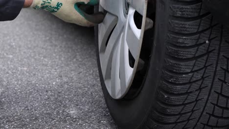 Extreme-close-up-caucasian-machinist-removing-a-hubcap-cover-on-a-car