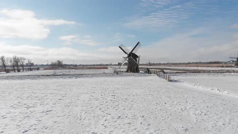 Winter-snow-covering-Dutch-windmills,-traditional-winter-aerial-landscape