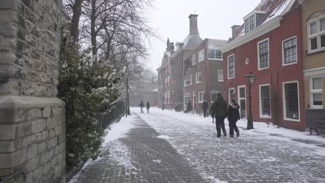 Snow-and-windy-Leiden-city-streets,-people-walking-through-cold-Dutch-town
