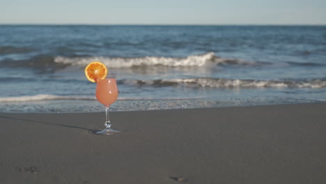 Tropical-orange-cocktail-drink-by-sea-beach-at-summer-holiday