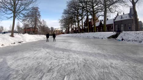 Zeitsprung-Zeigt-Holländischen-Schnee-Im-Winter-Mit-Menschen-Beim-Eislaufen-Und-Freizeitaktivitäten-Unter-Freiem-Himmel-Vor-Einem-Klaren-Blauen-Himmel,-Die-Dem-Fluss-Berkel-Folgen,-Vorbei-An-Berkelpoort-In-Richtung-Des-Großen-Kanals