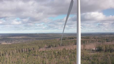 AERIAL-RISING---A-wind-turbine-in-a-forest-wind-energy-farm,-Sweden,-wide-shot