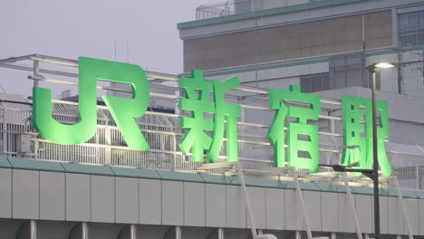 Beschilderung-Des-Bahnhofs-Shinjuku-Jr.-Auf-Dem-Dach-Eines-Nachts-Beleuchteten-Gebäudes-In-Tokio,-Japan