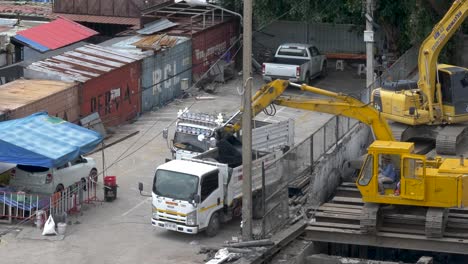 Gelber-Bagger-Belädt-Einen-Weißen-LKW-Auf-Einer-Baustelle