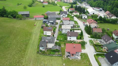 Flying-up-in-front-of-small-settlement-of-family-houses-between-beautiful-green-nature