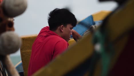 Ein-Junger-Vietnamesischer-Fischer-Sitzt-Auf-Seinem-Boot-Und-Entspannt-Sich-Für-Einen-Moment