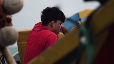 A-young-Vietnamese-fisherman-sits-on-his-boat-and-relaxes-for-a-moment